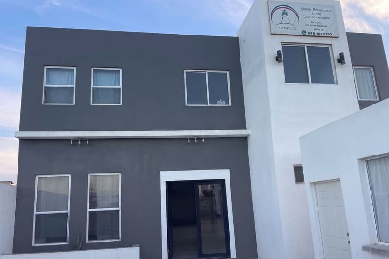 The front of the IPUL Ensenada church: a two-story gray and white building with the church sign on its tower.