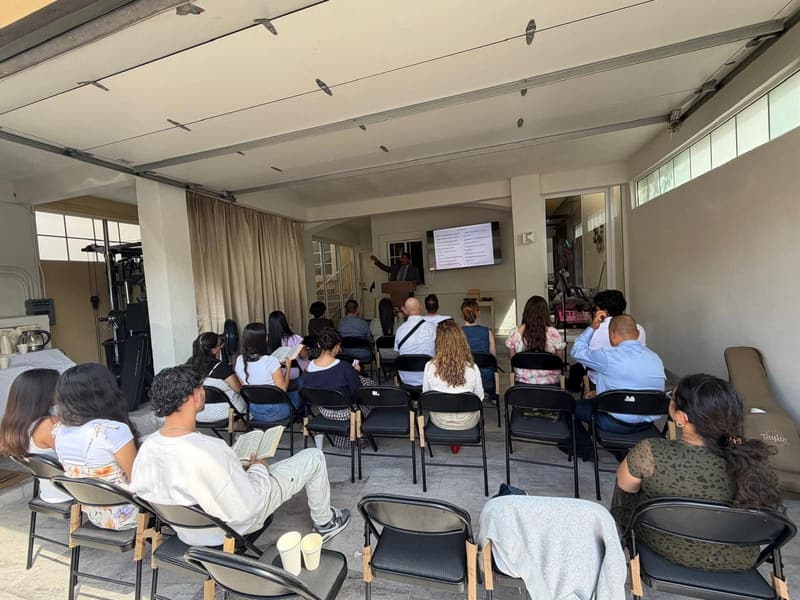 The Tijuana meeting room during a service, with people seated facing a screen at the front.